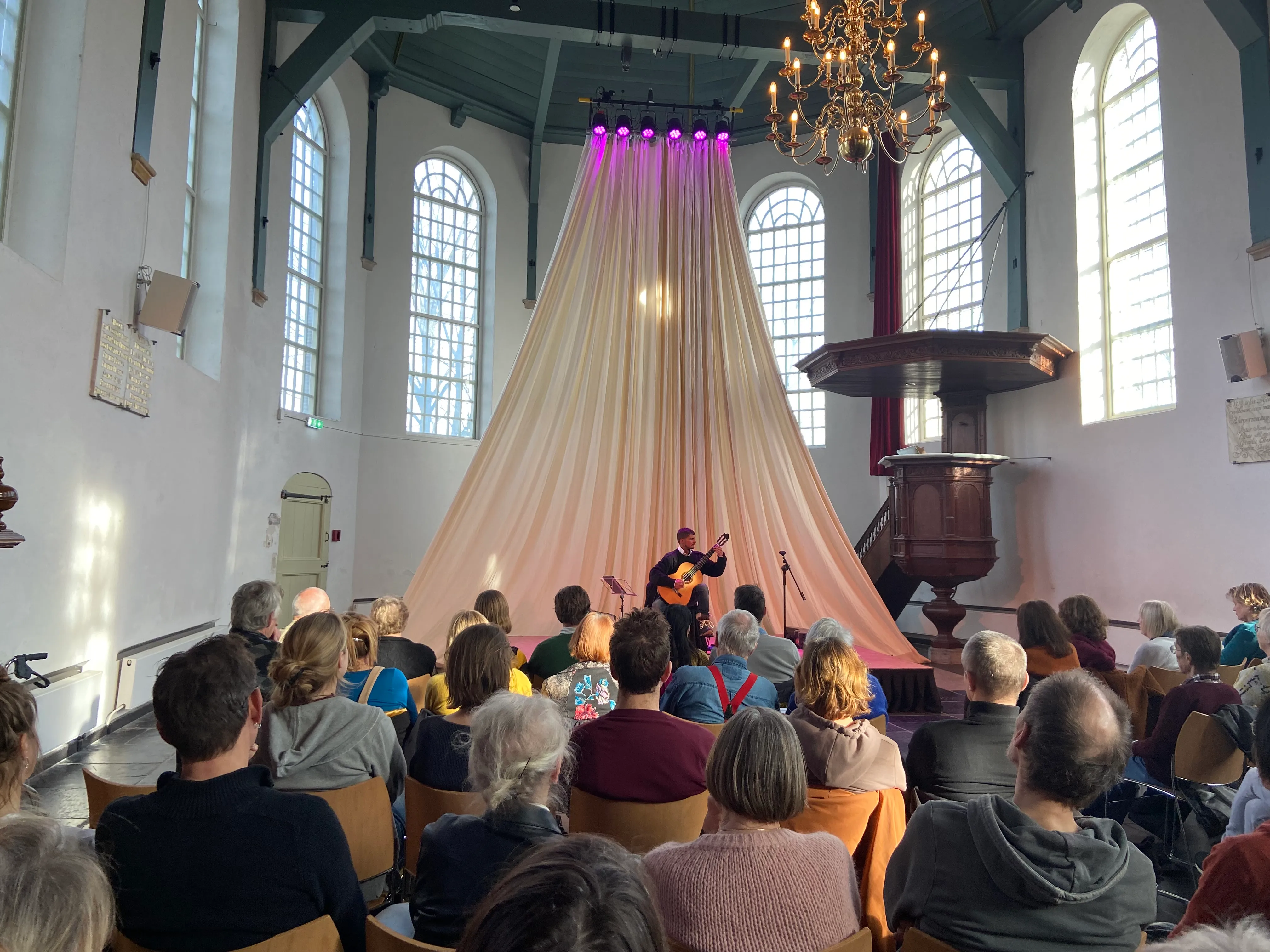 Silvan de Smit performing classical guitar for an audience in a church.