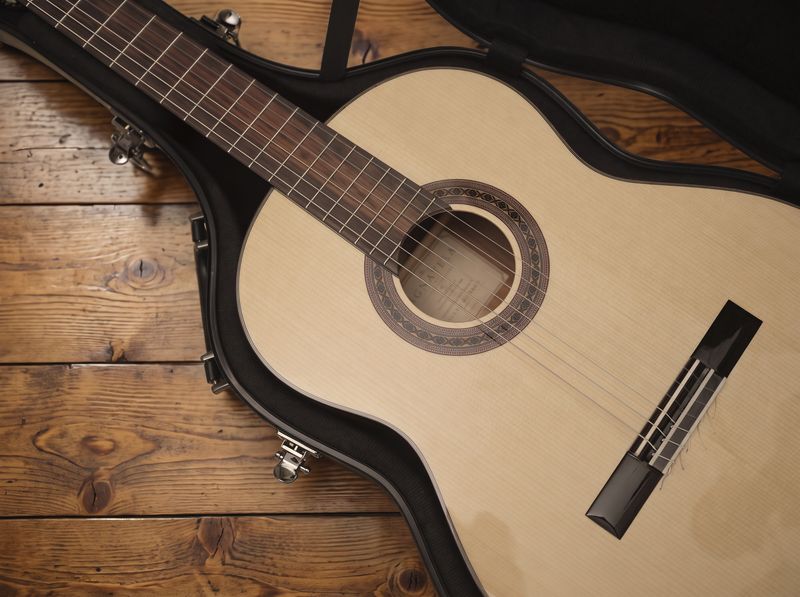 Klassieke Lignavela-gitaar in een open koffer op een oude houten vloer